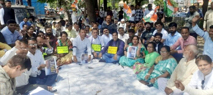 महात्मा गाँधी की प्रतिमा के समक्ष सत्याग्रह पर बैठे कांग्रेसी 